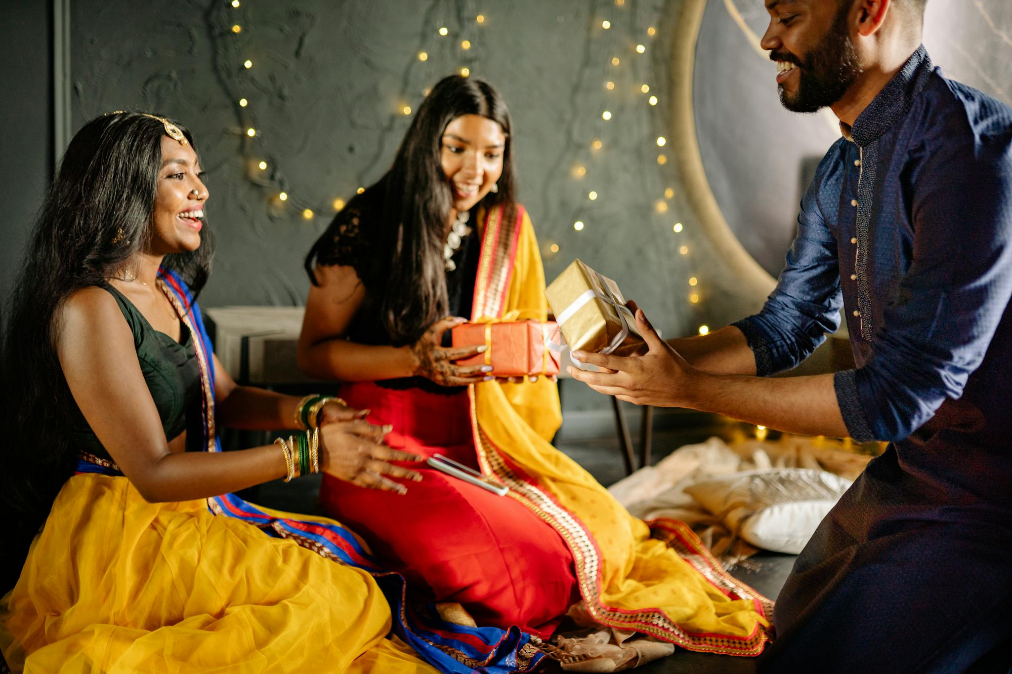 A group of South Asian adults exchanging gifts during a festive Diwali celebration indoors.