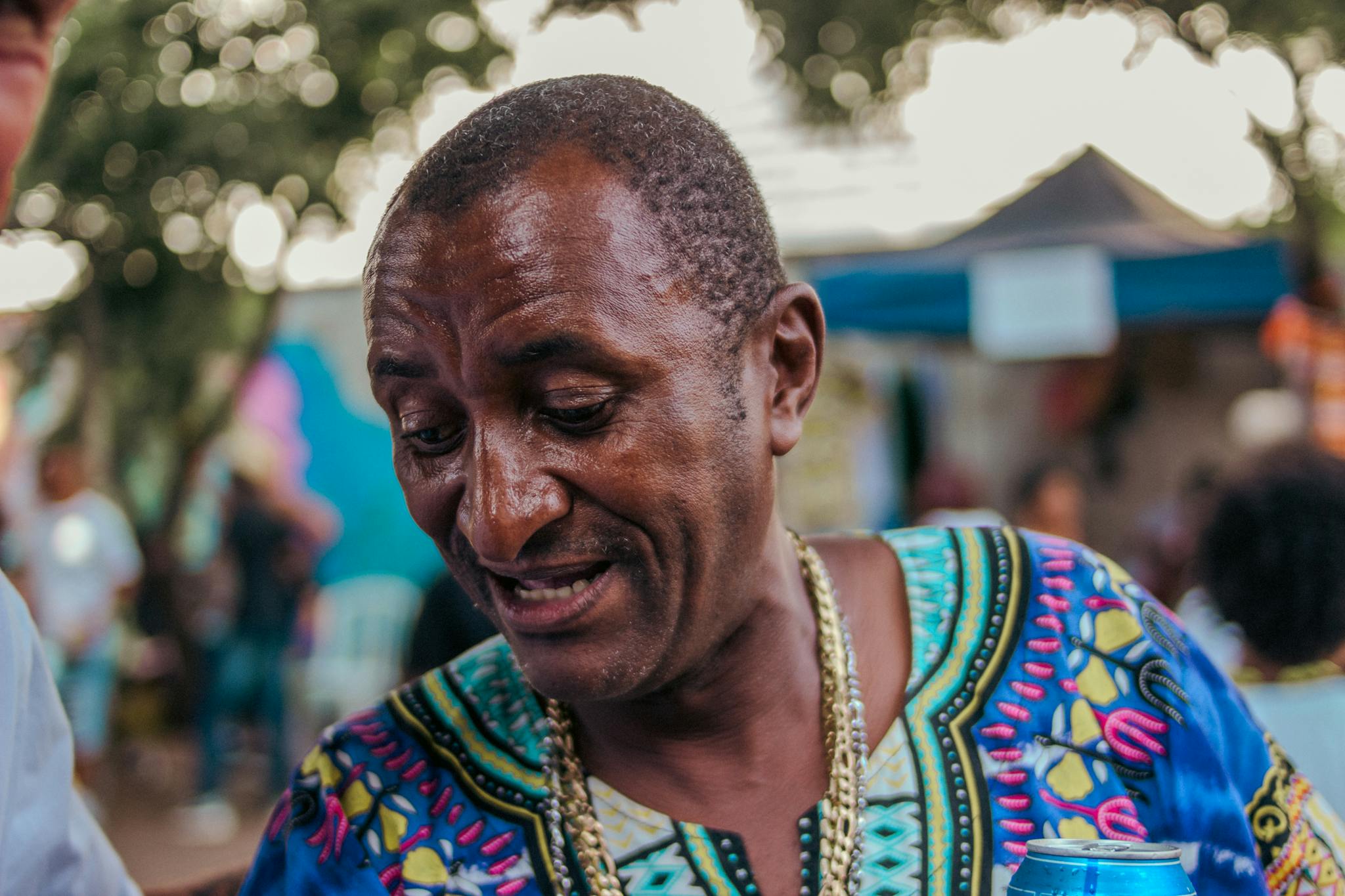 Colorful portrait of a man in traditional costume at an outdoor market, showcasing cultural vibrancy.